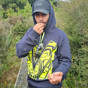 Raniera Smyth trying Mingimingi (Coprosma propinqua) and showing the seed in his other hand.