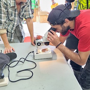 Raniera Smyth looking at an insect under microscope, with direction from Jesse Bythell.
